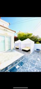 皮拉Exclusive Villa Larnaca - 8 plus sleeps - 2 min from BEACH - Big Private Pool的庭院设有两把白色长椅和房子