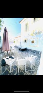 皮拉Exclusive Villa Larnaca - 8 plus sleeps - 2 min from BEACH - Big Private Pool的一座配有白色椅子和遮阳伞的庭院,一座建筑