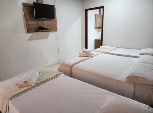 戈亚斯州上帕莱索Pousada Casa Rosa的客房设有三张床和一台平面电视。