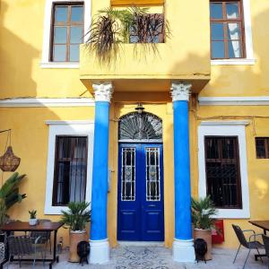罗德镇Rhodes Youth Hostel的蓝色柱子和蓝色门的黄色建筑