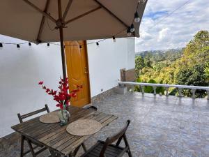 马里尼亚Cabañas con jacuzzi y chimenea - Casa Floral, Marinilla的阳台上配有一张带椅子和遮阳伞的木桌