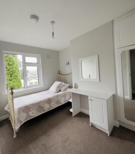 布莱辛顿Tully's Home, Tulfarris Village, Wicklow的一间卧室配有一张床、一张书桌和一个窗户。