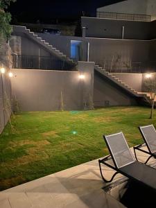古穆斯卢克İBAK Apartments的庭院里设有两把椅子,晚上有院子
