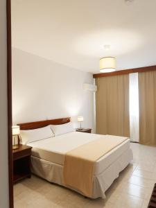 圣玛丽亚Hotel Central Santa Maria的卧室配有一张白色的大床和两张桌子