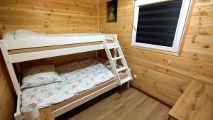 HartowiecLubkowa chata的木制客房的双层床,设有窗户