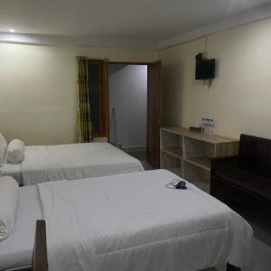 纳闽巴霍Pesona Room and restaurant的酒店客房设有两张床和电视。