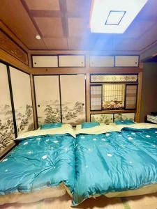 富士吉田市T&T Fujiyama Guest House的一间卧室配有一张蓝色床单