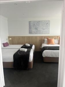 纳甘比尼冈比海滨汽车旅馆的两张位于酒店客房的床,配有两张sidx sidx单人床