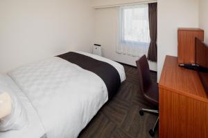 熊本熊本东急REI酒店的一间卧室配有一张床、一张书桌和一个窗户。