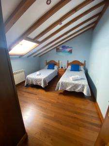 RibadedevaCasa Balmori El Peral的配有蓝色墙壁和木地板的客房中的两张床