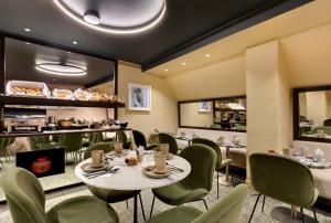 巴黎乐瑟纳酒店的餐厅设有桌子、绿色椅子和柜台