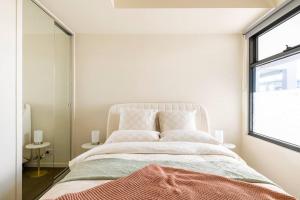 墨尔本Beachside flat with free parking的白色的卧室设有一张大床和一个窗户