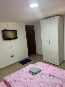 代斯波托瓦茨ŽUBOR VRELA的卧室配有粉红色的床和墙上的电视。