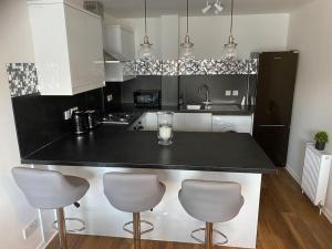 格拉斯哥Perfectly situated luxury 2 bedroom apartment的厨房配有黑色柜台和3个吧台凳
