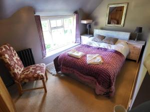 凯尼尔沃思Castle Hill Cottage on a Scheduled Monument的卧室配有床、椅子和窗户。