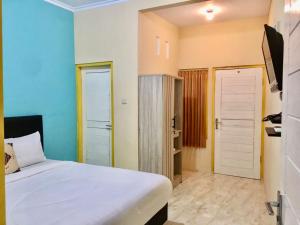 大松巴哇GRAND KHALIFAH Guesthouse的卧室配有白色的床和门