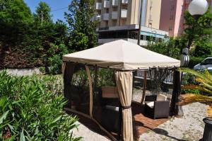 里米尼艾斯德拉酒店的一把大雨伞坐在花园内,花园下方摆放着椅子