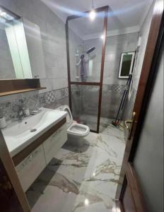 纳祖尔Nador cornich Apartement的浴室配有卫生间、盥洗盆和淋浴。