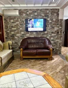 纳祖尔Nador cornich Apartement的客厅里的真皮沙发,客厅里设有石墙电视
