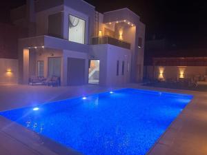 杰里科فلل ليليان الحديثة的一座大型游泳池,在晚上在房子前面