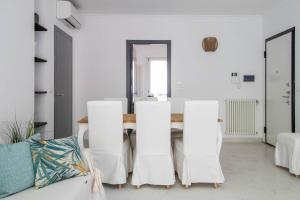 波托菲诺Elios by PortofinoHomes的一间拥有白色墙壁和桌椅的用餐室