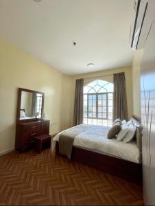 马斯喀特Deluxe Apartment的一间卧室设有一张床和一个大窗户