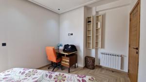莫纳斯提尔Lovely apartment in Monastir的一间卧室配有书桌、一张床和一把椅子