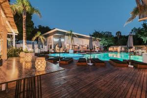 伊利索斯Bamboo Suites Hotel的毗邻度假酒店的带椅子和遮阳伞的游泳池