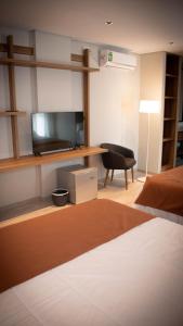 OlivaUrban Suites Oliva的配有床、电视和椅子的房间