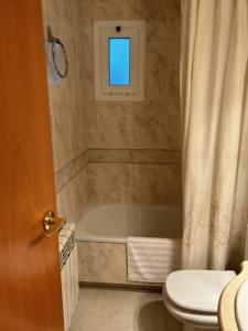 滨海阿雷尼斯Apartament Port的一间带卫生间和浴缸的浴室以及窗户。