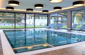 索拉加Wellness Hotel Dolomia的大楼内带椅子的大型游泳池
