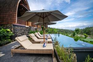 卡朗阿森Lumbung Seraya Villa的一组椅子和一把遮阳伞,位于游泳池旁