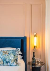 耶路撒冷Damson - Machne Yehuda Hotel的一张带蓝色床头板的床和一张带酒杯的桌子