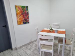 里奥加耶戈斯Hermoso departamento con patio en Rio Gallegos的一张白色的桌子和椅子,墙上挂着一幅画