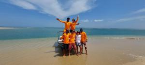 卡尔皮蒂耶BLUE WAVES kite surfing beach resort的一群身穿橙色衬衫的人站在海滩上