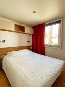 雷日卡普费雷MOBIL HOME 6 personnes Cap Ferret的卧室配有白色的床和窗户。