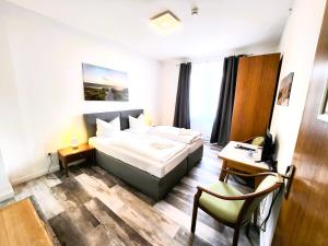 库克斯港City Center Hotel Garni Cuxhaven的酒店客房配有一张床、一张桌子和一把椅子。