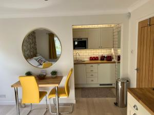 利明顿No 64 Bed and Breakfast的厨房配有桌子、黄色椅子和镜子