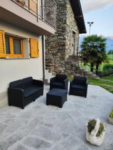 松德里奥Casa Vacanza Relax Sondrio的一个带两把黑色椅子的庭院和一座建筑