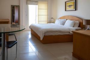 麦纳麦曼苏里公寓式酒店的一间卧室配有一张床和一张玻璃桌