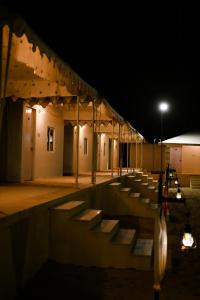 斋沙默尔Shrinath Desert Camp的一座晚上有长椅的建筑