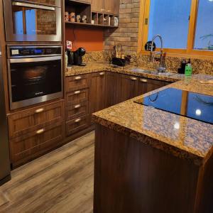 卡曼杜卡亚Chalé Colorado Vibe的厨房配有木制橱柜和花岗岩台面