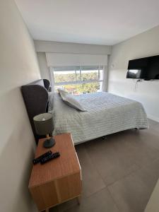 埃斯特角城Torre Green Life FullAmenities的一间卧室配有一张床、一台电视和一张桌子