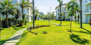 西迪拉哈尔Cosy Apartment with sea view的一座种植了棕榈树和建筑的绿色公园