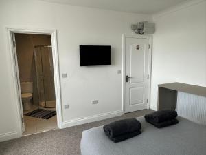 亨顿Sunny Modern, 1 Bed Flat, 15 Mins Away From Central London的一间设有两把枕头的墙上电视的房间