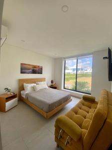吉拉尔多特Hermosa casa de campo con piscina Girardot flandes的一间卧室配有一张床、一张沙发和一个窗口