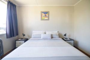 陶波Turangi Home Family Size的一间卧室配有一张带2个床头柜的大型白色床