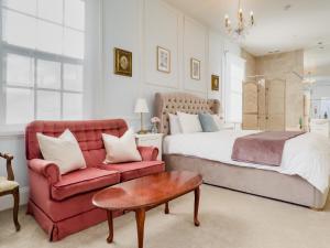 朗塞斯顿爱丽丝度假屋的一间卧室配有一张床和一张红色的沙发