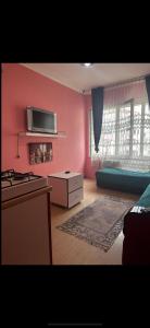 伯萨Uraz Apart的一间带粉红色墙壁的客厅和一间带炉灶的厨房