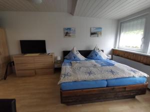 库克斯港Pension Haus Erika的一间卧室配有一张带蓝色枕头的床和电视。